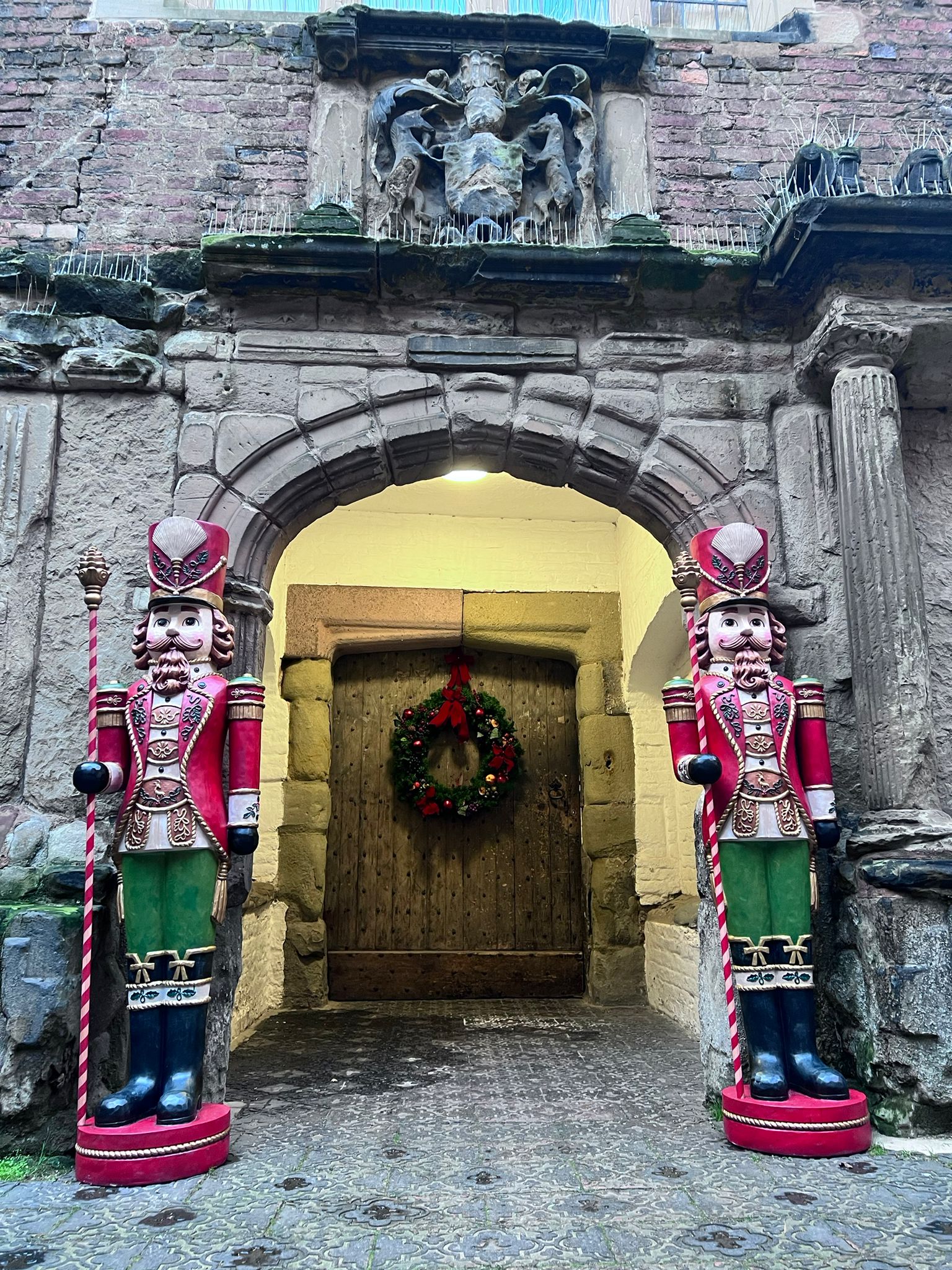 photo taken outside castle door to the Great Hall and porch, with a Christmas wreath and two nutcracker statues