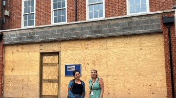 Photo of Cllr Dean and Cllr Arkney outside the former Peel cafe. Wooden hoarding is outside the front of the building